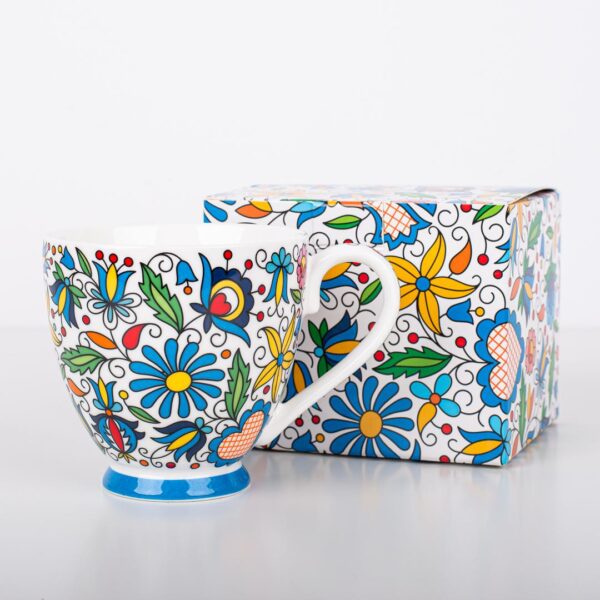 A vibrant Polish Folk Art Mug with a hand-painted floral design inspired by the Łowicz region, shown alongside a matching decorative box. The mug features colorful flowers and leaves on a white ceramic background.