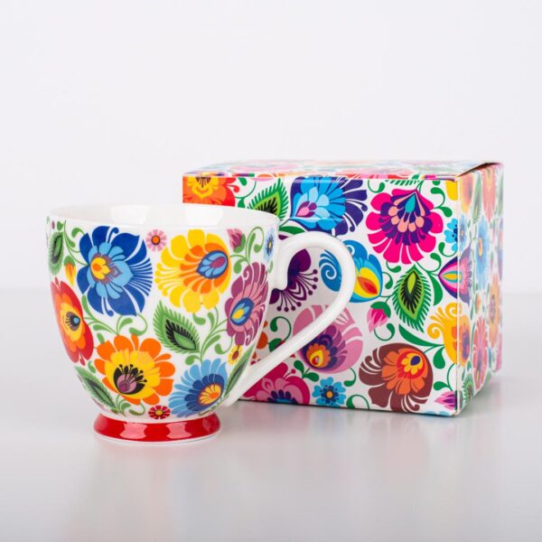 A vibrant Polish Folk Art Mug with hand-painted traditional Łowicz floral designs in bright colors, shown next to a matching decorative box with the same colorful floral pattern. The mug features a white ceramic background with a red base.