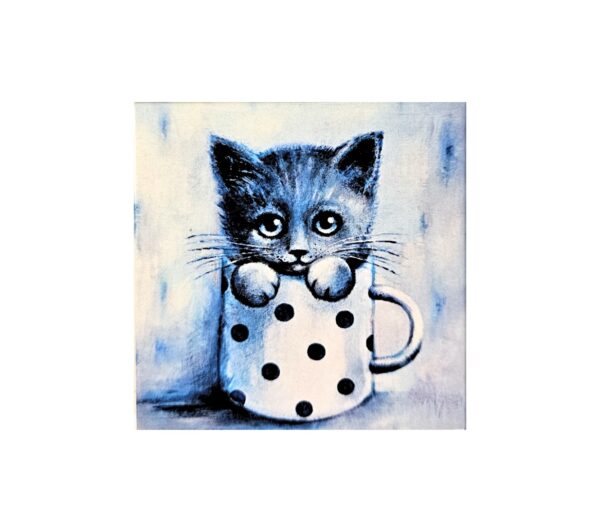 Magnet showing a cute kitten with big eyes sitting inside a white mug with black polka dots.
