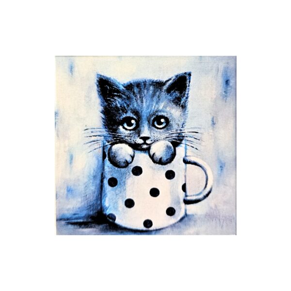 Magnet showing a cute kitten with big eyes sitting inside a white mug with black polka dots.