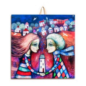 Ceramic tile with a colorful illustration of a couple holding a house together, with a whimsical town and trees in the background.
