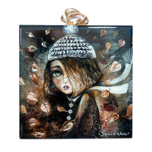 Ceramic tile artwork of a whimsical girl in a knitted hat and scarf with autumn leaves swirling around her on a brown textured background.