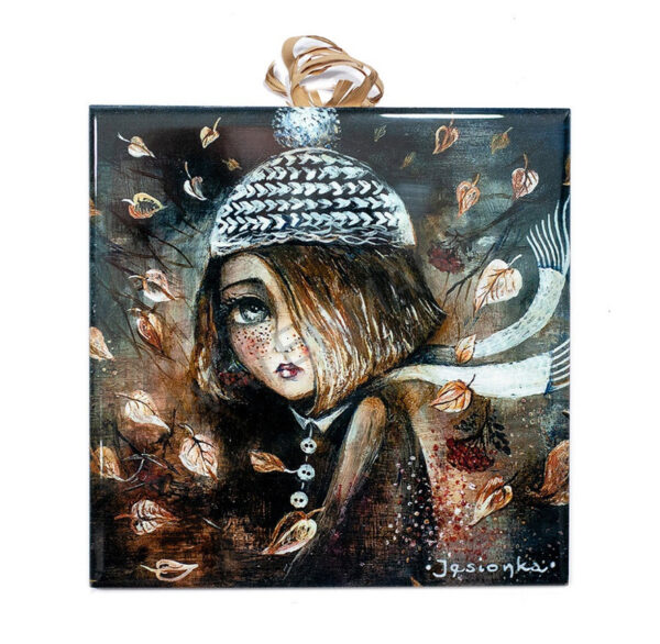 Ceramic tile artwork of a whimsical girl in a knitted hat and scarf with autumn leaves swirling around her on a brown textured background.