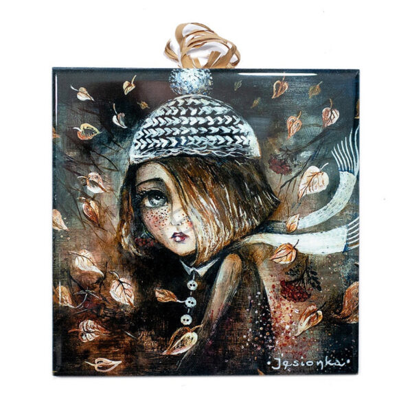Ceramic tile artwork of a whimsical girl in a knitted hat and scarf with autumn leaves swirling around her on a brown textured background.