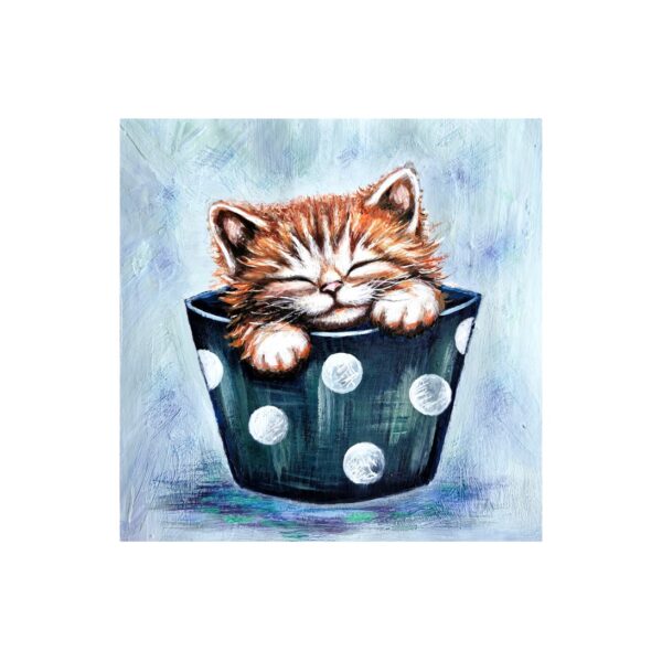 Magnet showing a ginger kitten with eyes closed, sleeping inside a dark cup with white polka dots.