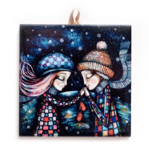 Ceramic tile artwork of a couple in colorful winter clothing and hats, holding hands tenderly under a snowy, starry night sky.
