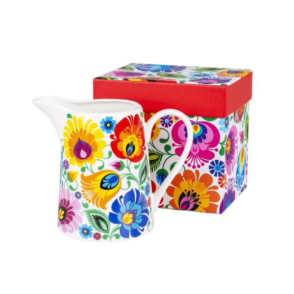 Colorful ceramic milk jug with vibrant floral folk pattern next to a matching decorative gift box.