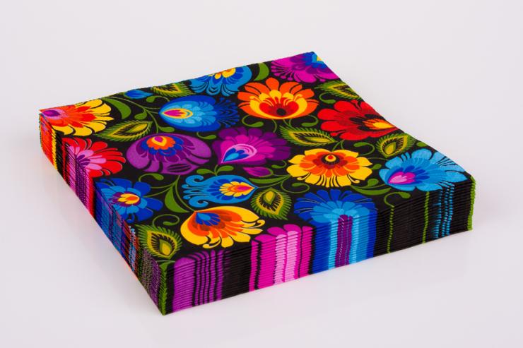 Stack of colorful floral patterned paper napkins with bright multicolor flowers on a black background